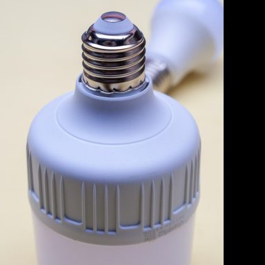 Schraubgewinde einer Energiesparlampe in grauer Kunststofffassung.