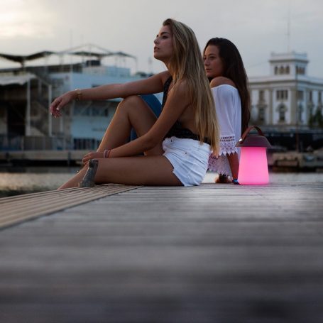 Zwei Frauen sitzen am Ufer, die eine blickt nachdenklich in die Ferne, eine Lampe leuchtet.