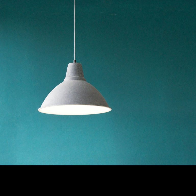 Hängelampe in minimalistischen Stil vor einer türkisfarbenen Wand.