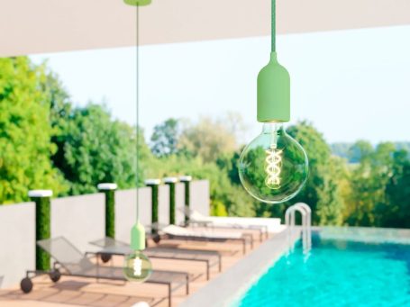 Beleuchtete Terrassenlounge mit Pendelleuchten und Swimmingpool bei Tageslicht.