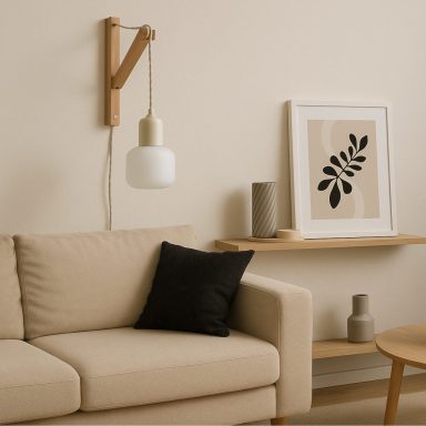 Beige Couch mit schwarzem Kissen, hängender Lampe und Wandregal mit zwei Dekoobjekten.