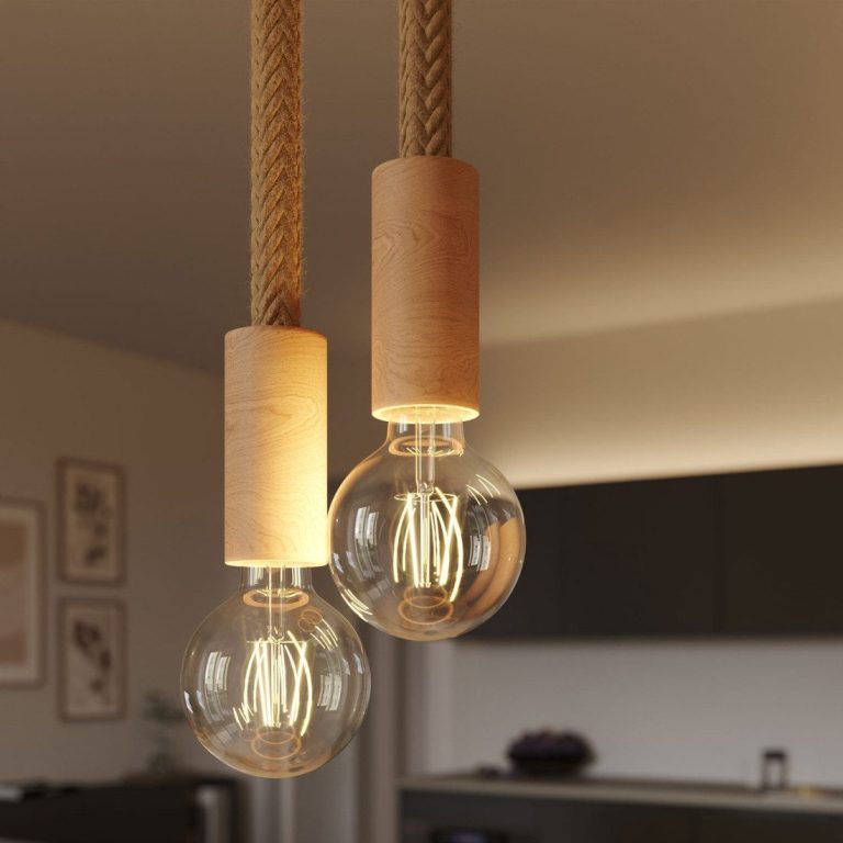 Zwei Edison-Glühbirnen mit Holzhaltern hängen an Seilen in einem modernen Raum.