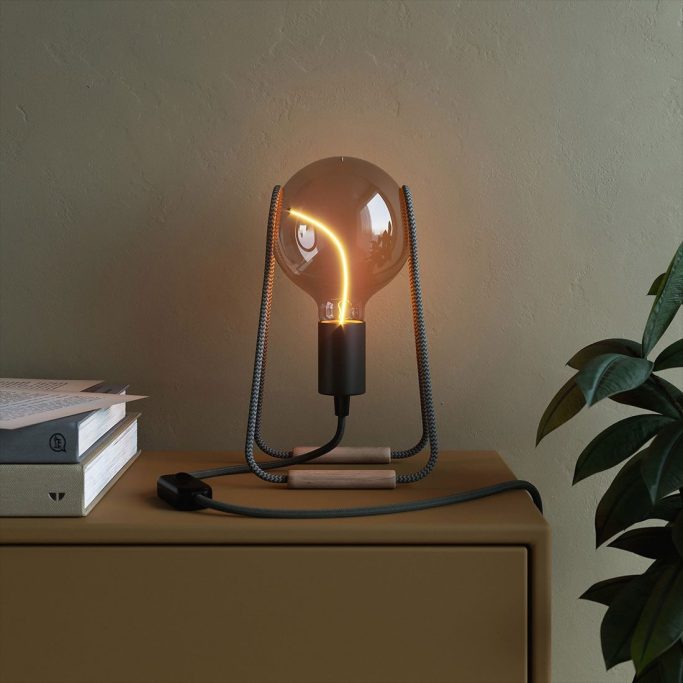 Eine moderne Tischlampe mit glühendem Glühbirnen-Design auf einem Holztisch.