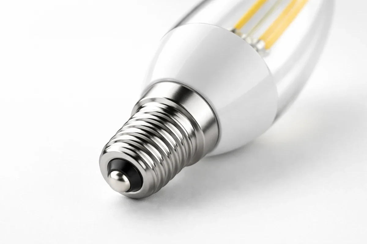 Nahaufnahme eines E14 LED-Leuchtmittels mit deutlich sichtbarem 14 mm Schraubsockel auf hellem Studiohintergrund.