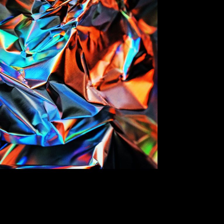 Bunte, glänzende Metalloberfläche mit Falten und Reflexionen.